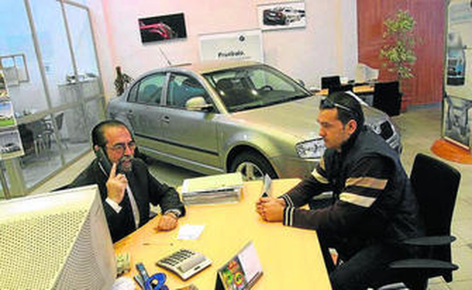 Un vendedor de vehículos con un cliente en un concesionario.