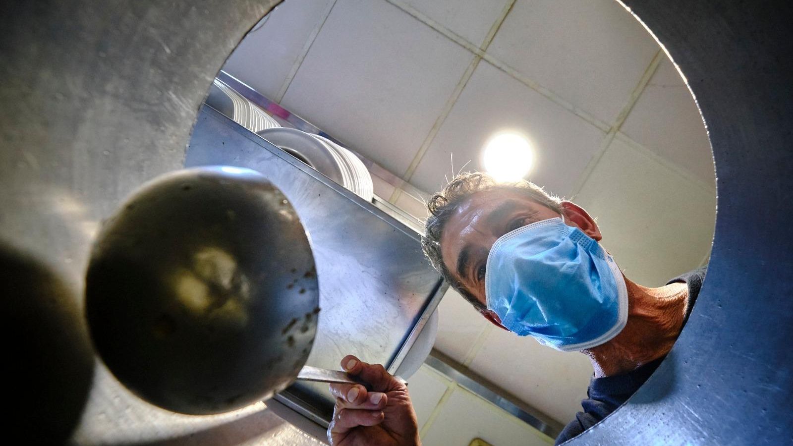 Un empleado del bar asomado a la olla de caracoles.