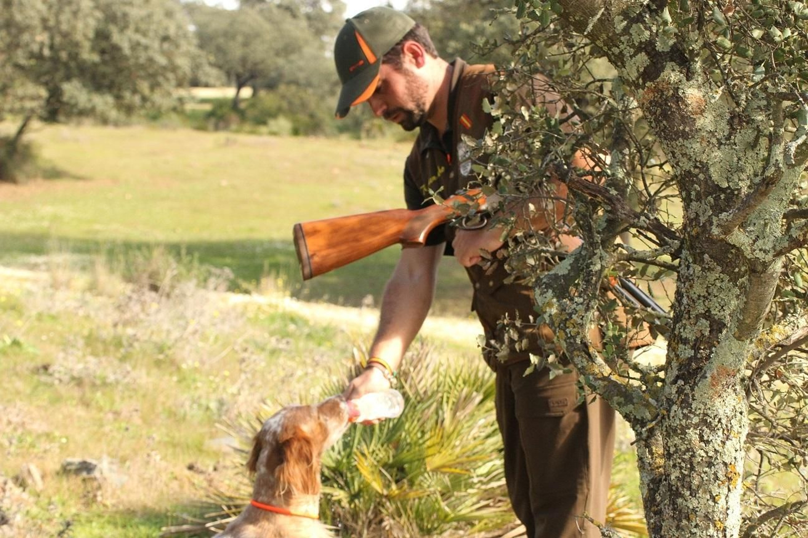 Un cazador da de comer a un perro.
