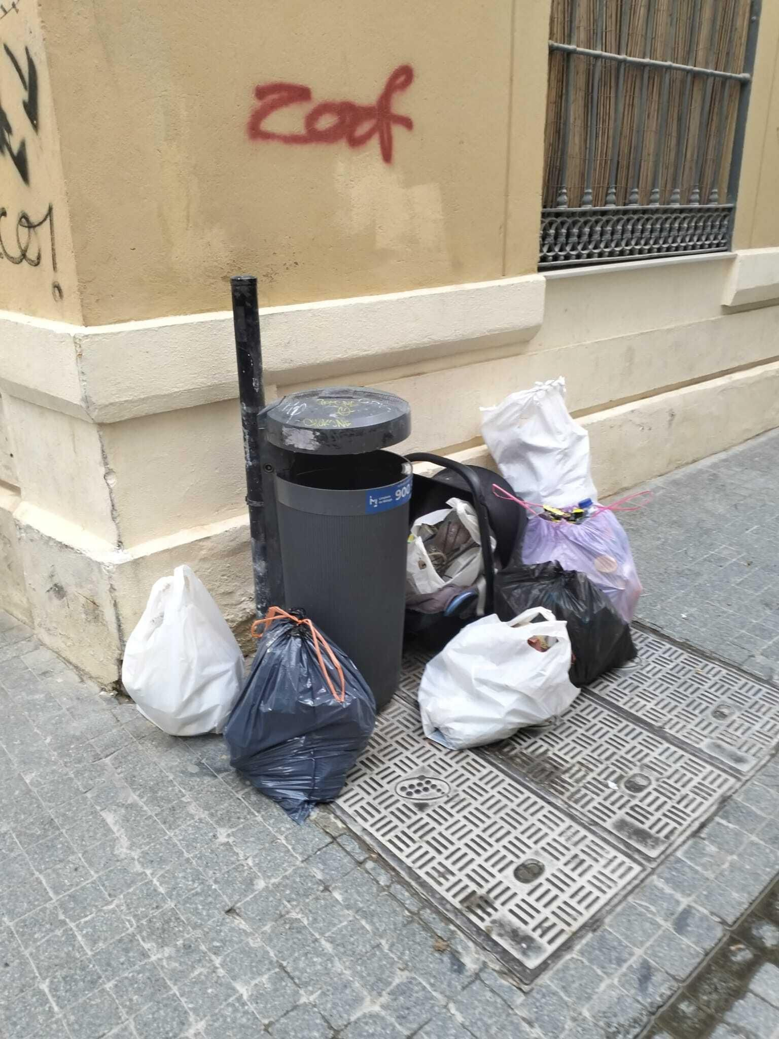 Una papelera rodeada de basura.