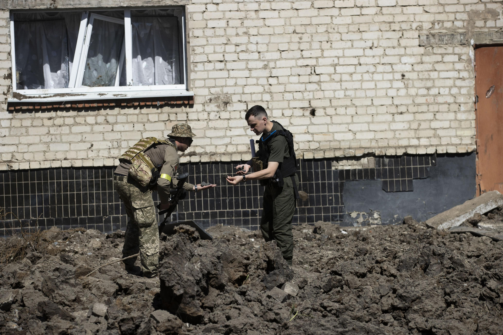 Militares ucranianos recorren el patio de una escuela que fue impactado por un misil ruso de madrugada en Jarkov.