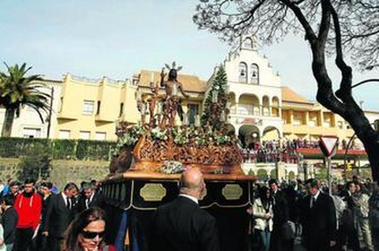 El paso de misterio, arropado por cientos de devotos, reemprende la marcha tras el singular acto frente a la residencia Santa Teresa Jornet, al fondo.