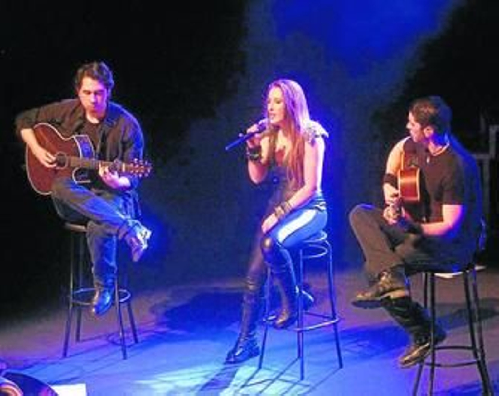 Malú interpretando 'Así lo haré' en acústico acompañada de dos guitarras.