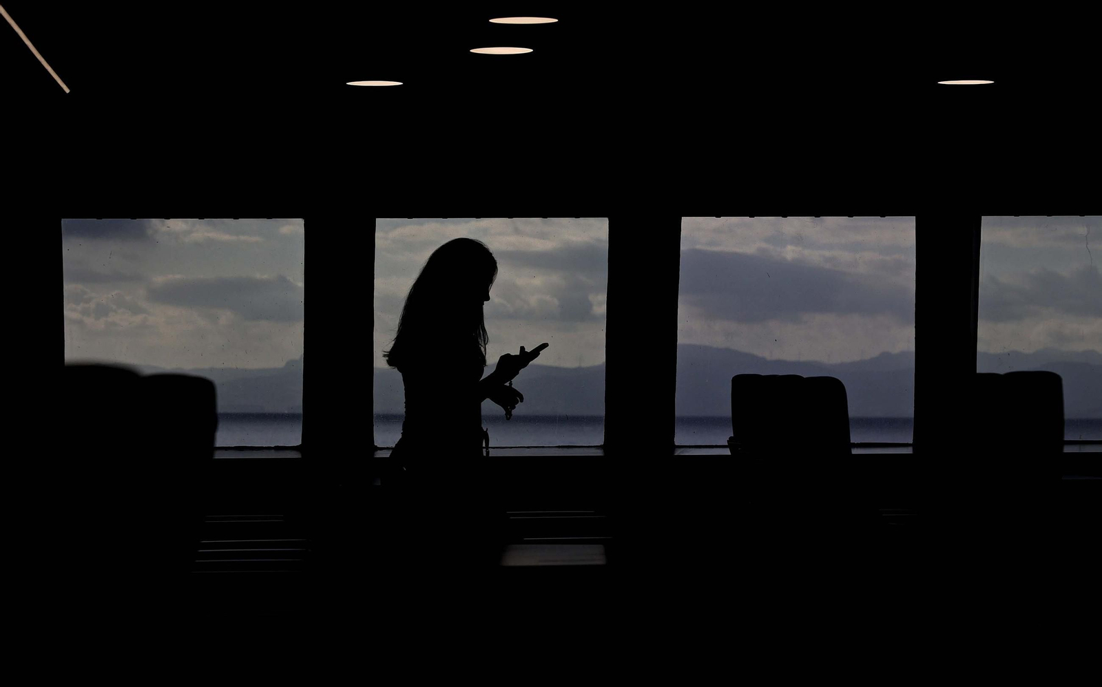 Una pasajera consulta su móvil mientras atraviesa el Estrecho en ferry.