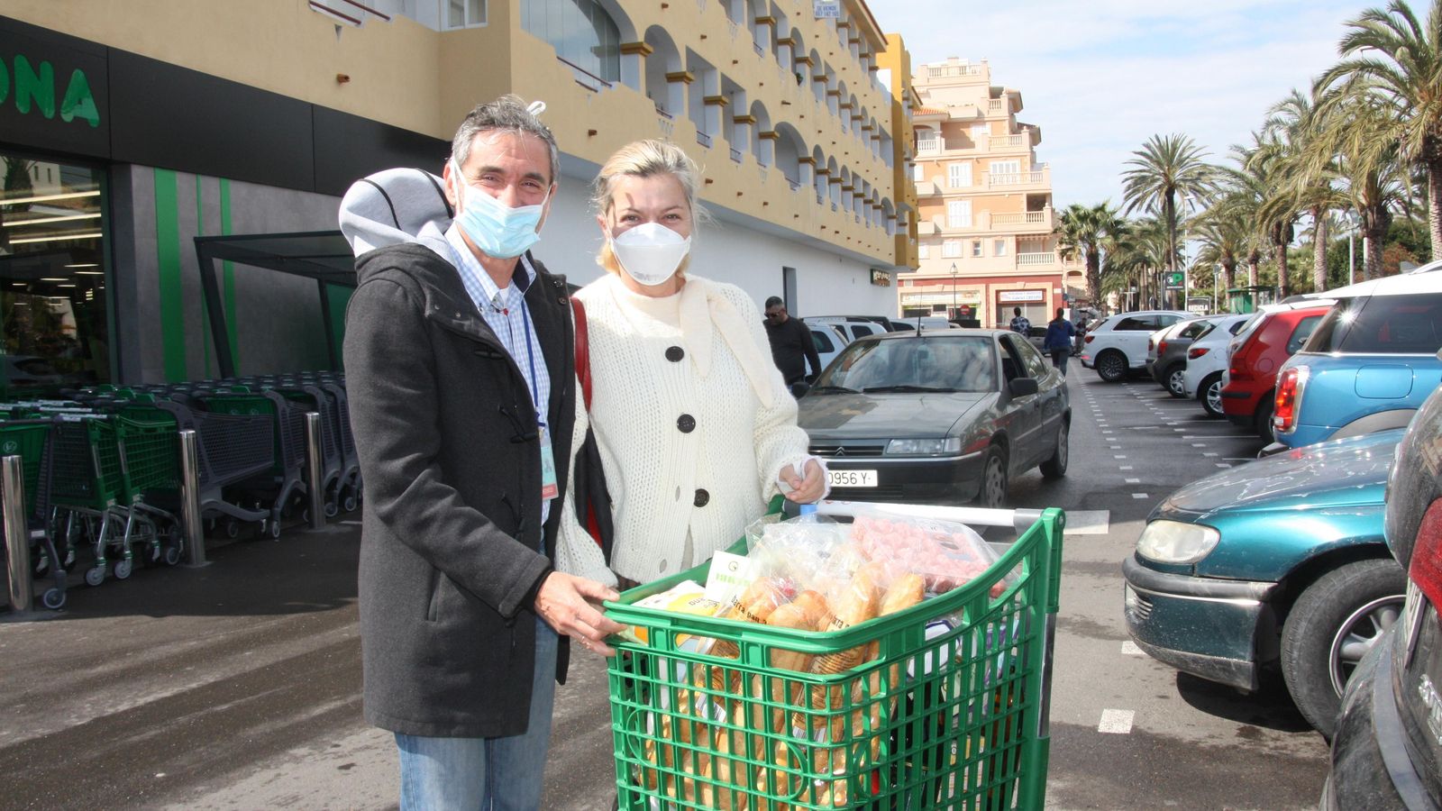Dos clientes, tras hacer la compra con mascarillas.