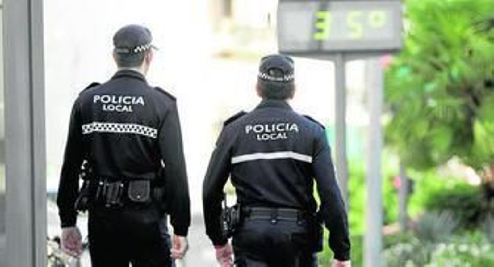 Dos policías locales pasan por un termómetro que marca 35 grados, ayer en Los Remedios.