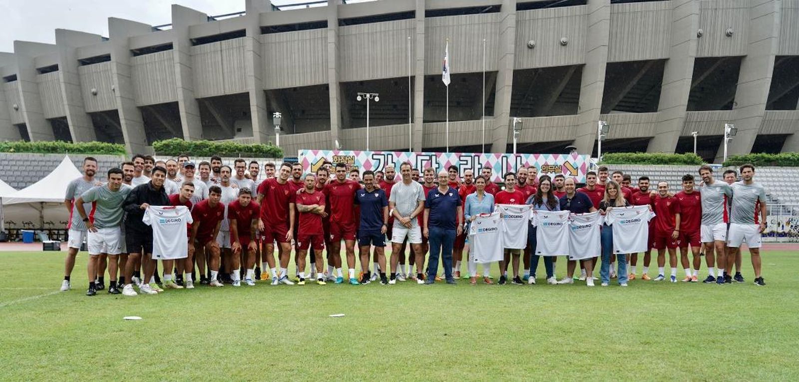 Foto de familia del Sevilla con algunos operarios ante el Estadio Olímpico de Seúl.
