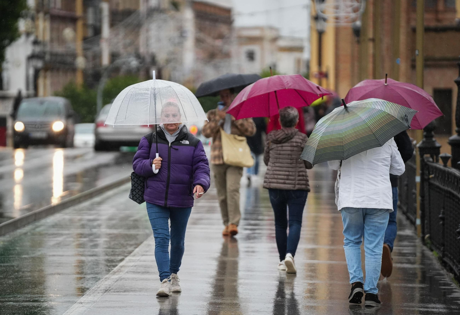 Gente con paraguas en el puente de Triana.