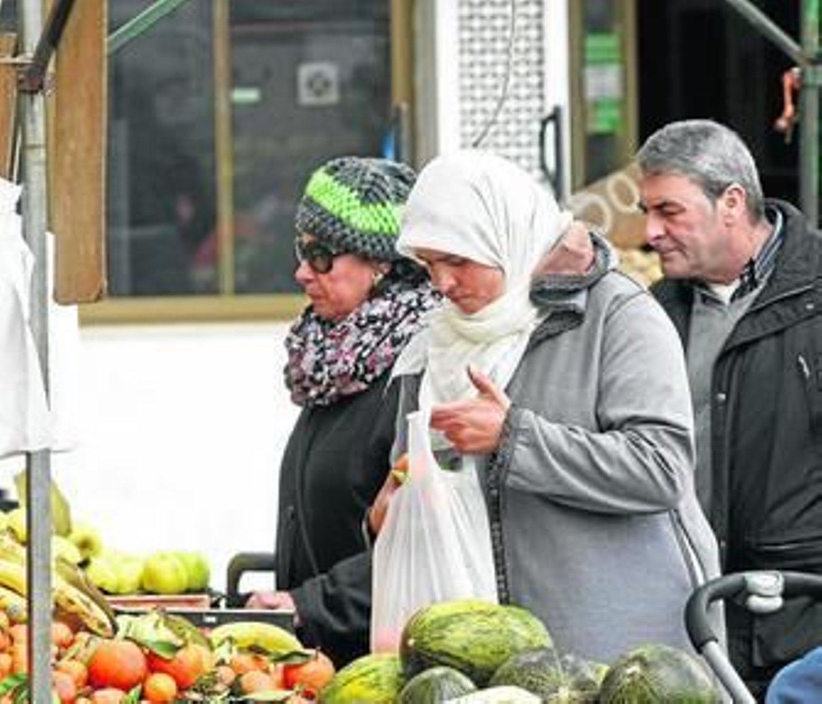 Una mujer musulmana compra fruta en un puesto del mercado.