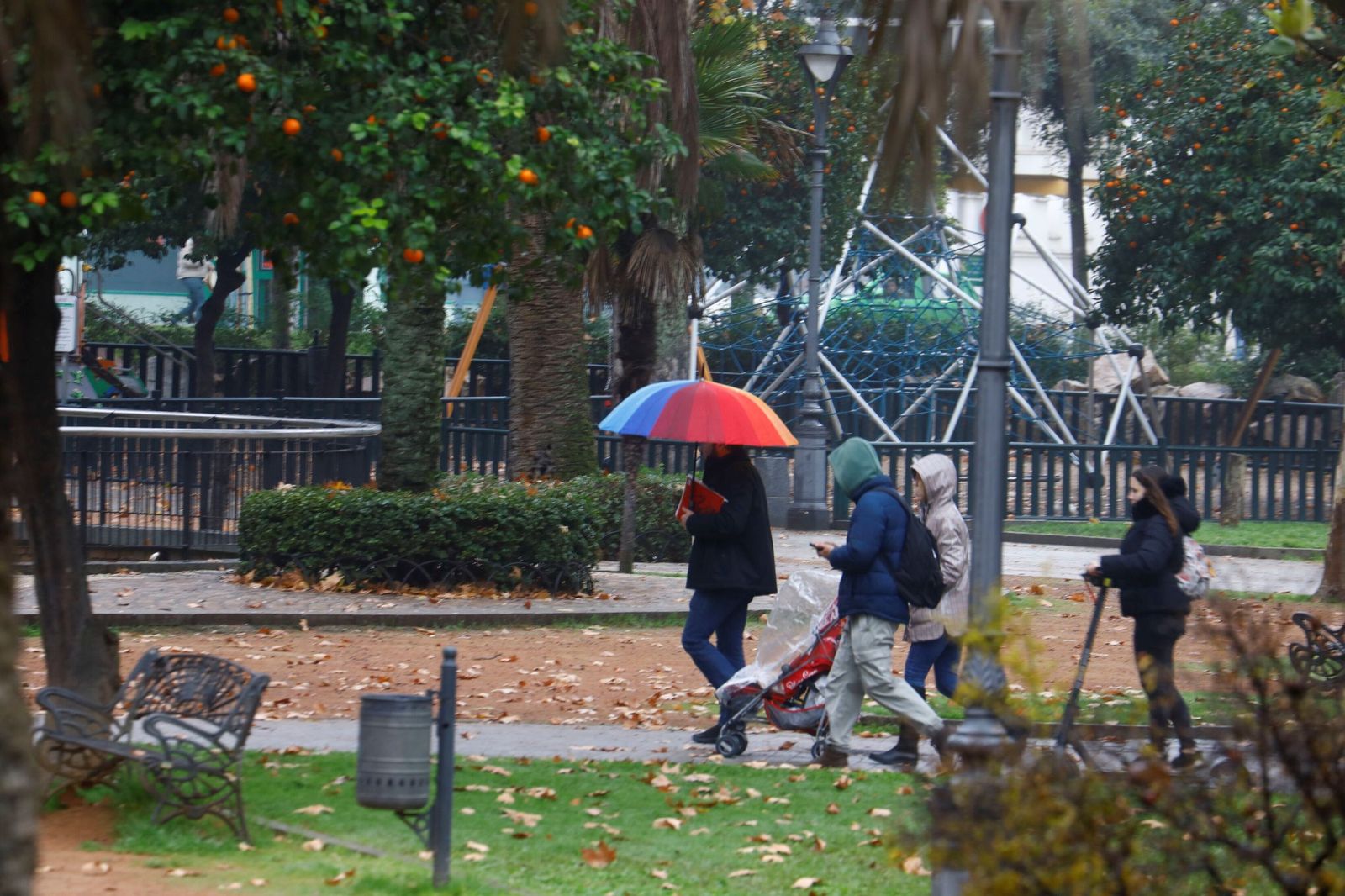 Varias personas cruzan los jardines de la Agricultura bajo paraguas.