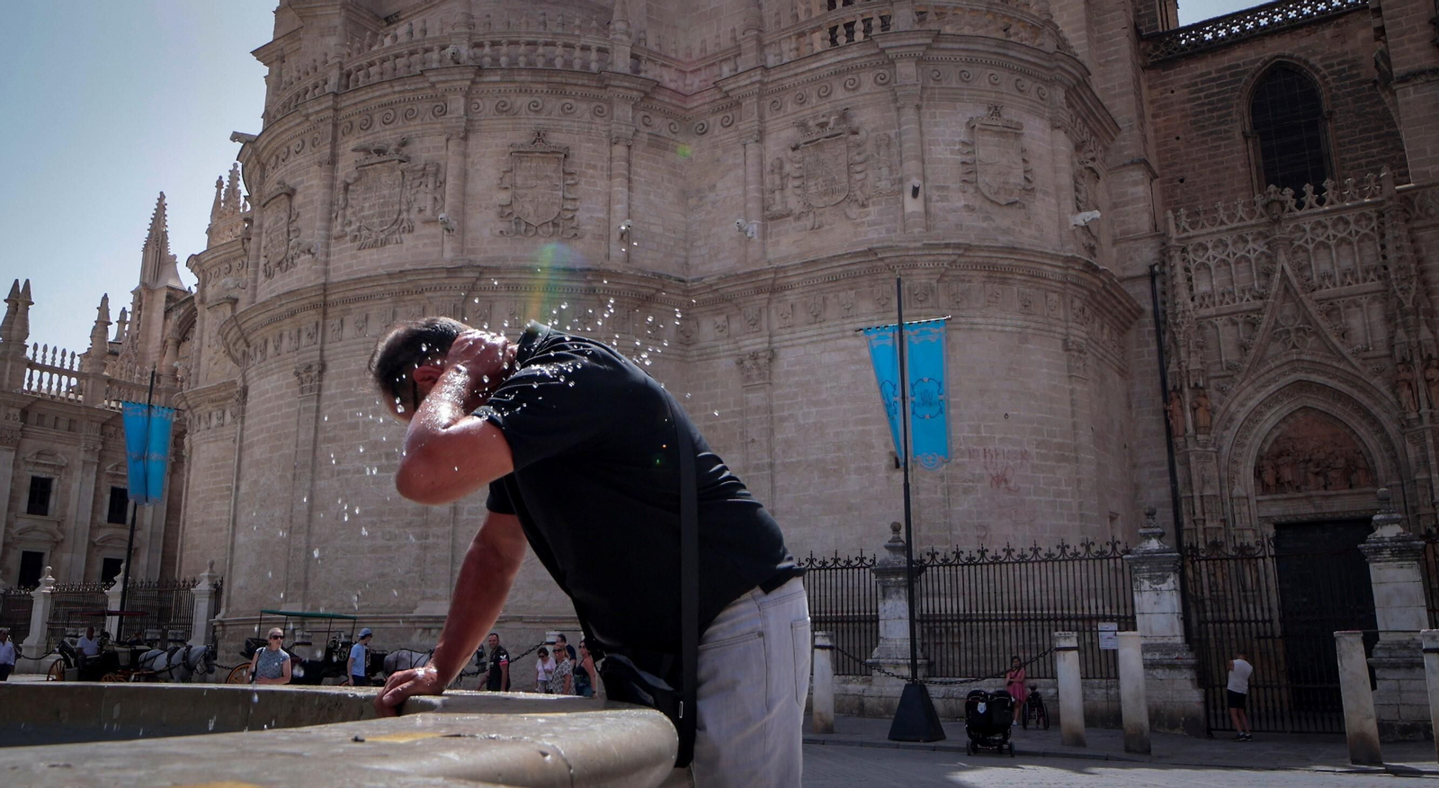 Un turista se refresca con el agua de una fuente junto a la Catedral.