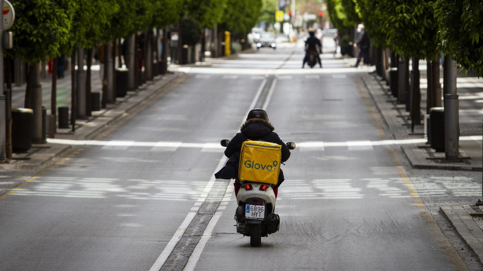 Un repartidor a domicilio circula con su moto por calle Recogidas durante el estado de alarma