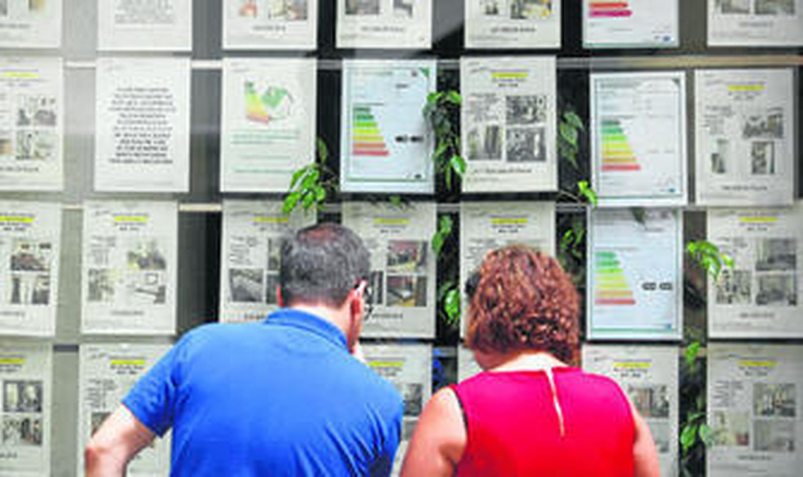 Dos personas miran el escaparate de una inmobiliaria.